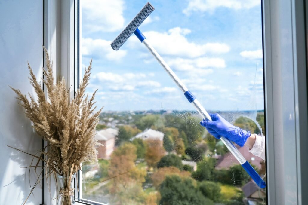 Employee hand in rubber protective glove cleans window with foam and puller. General spring cleaning