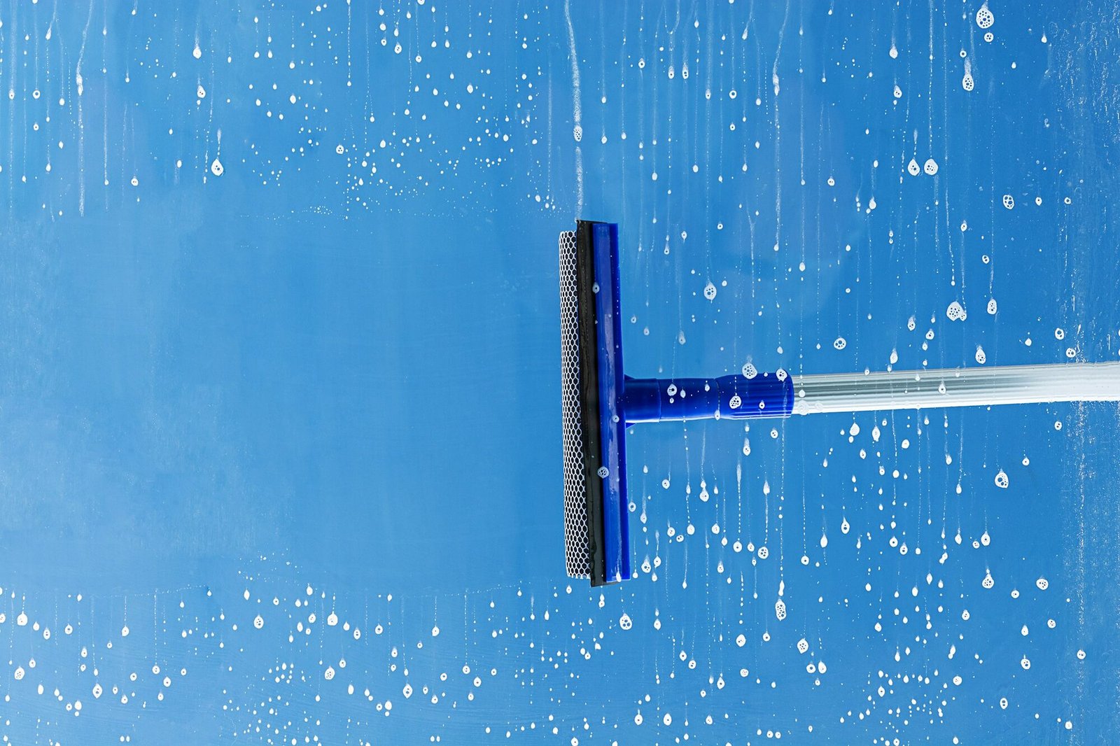 Rubber squeegee cleans window. Clears a stripe of soaped window. Cleaning service concept.